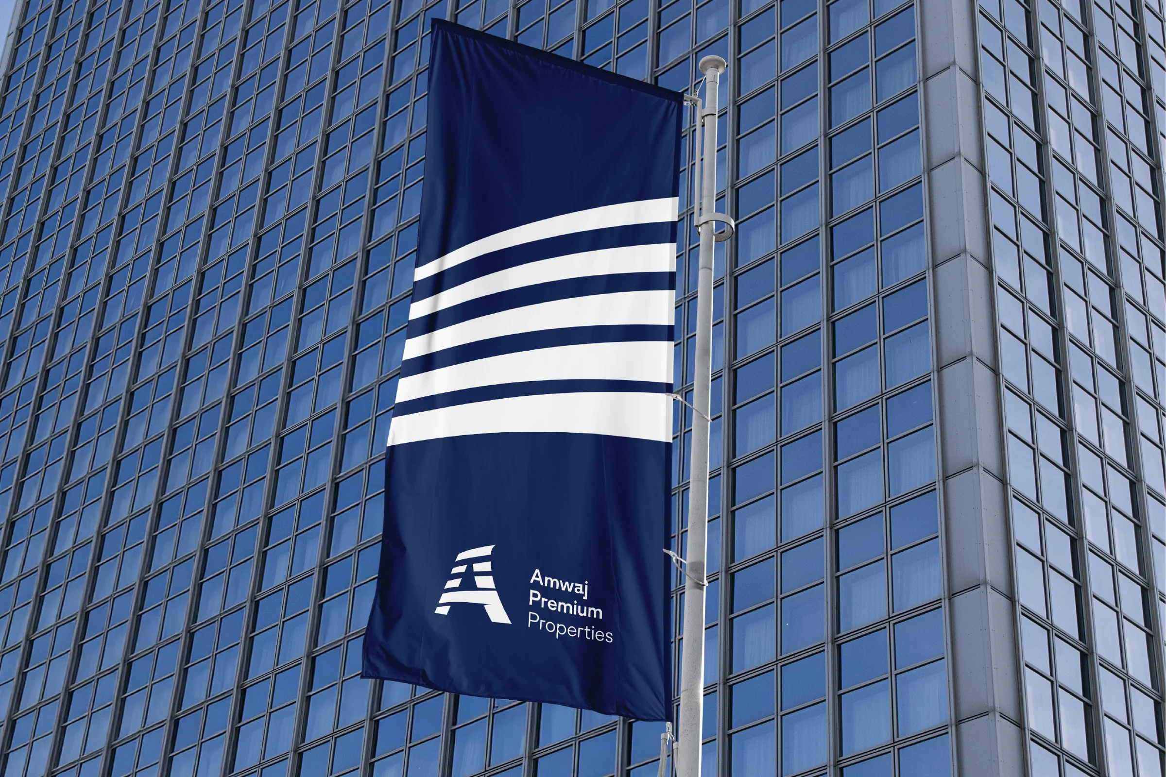 A navy banner flag on a pole before a glass tower, with five white bands across its upper half and the white logo below.