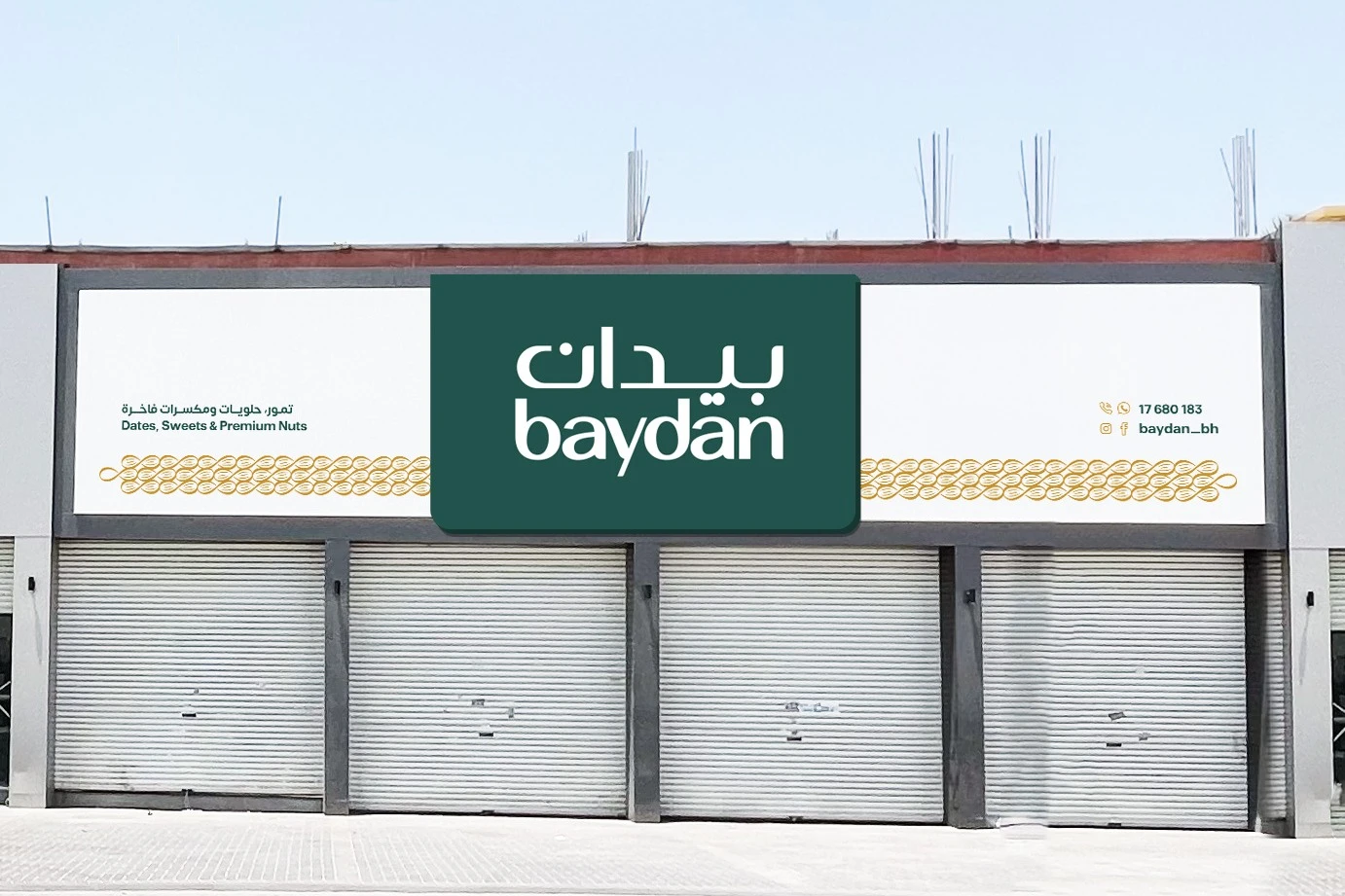 A shopfront fascia with the logo in white on a green panel, flanked by a band of gold almonds, above closed shutters.