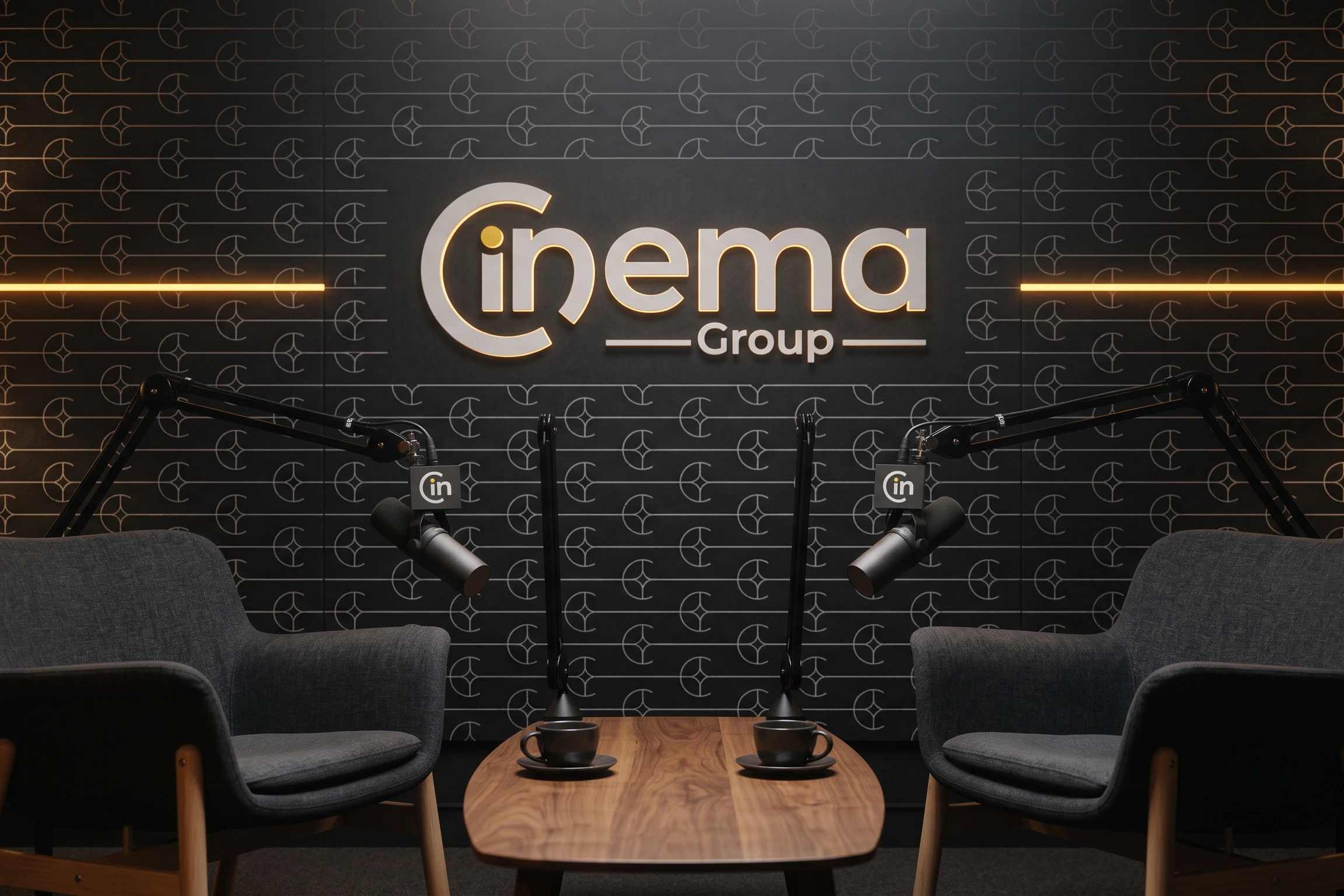 A podcast studio: two armchairs and two microphones carrying the symbol, before a wall of the pattern with the logo lit in the middle.