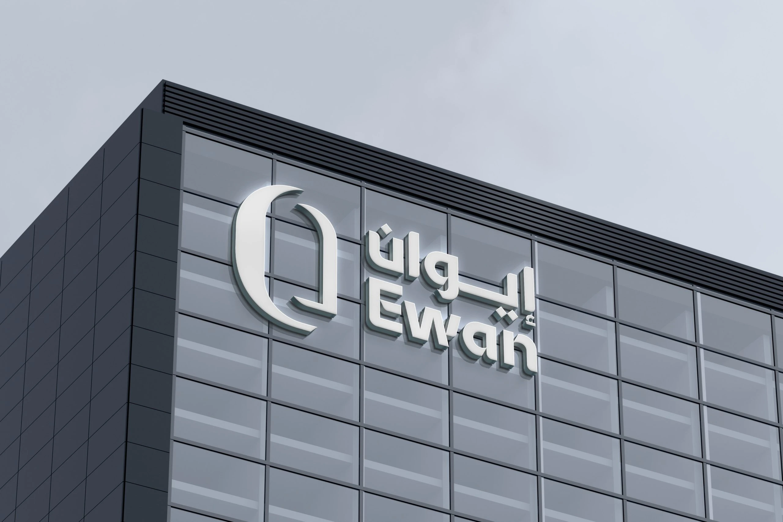 The Ewan logo as white 3D lettering high on a dark glass building: the arched mark beside إيوان above Ewan, under a pale grey sky.