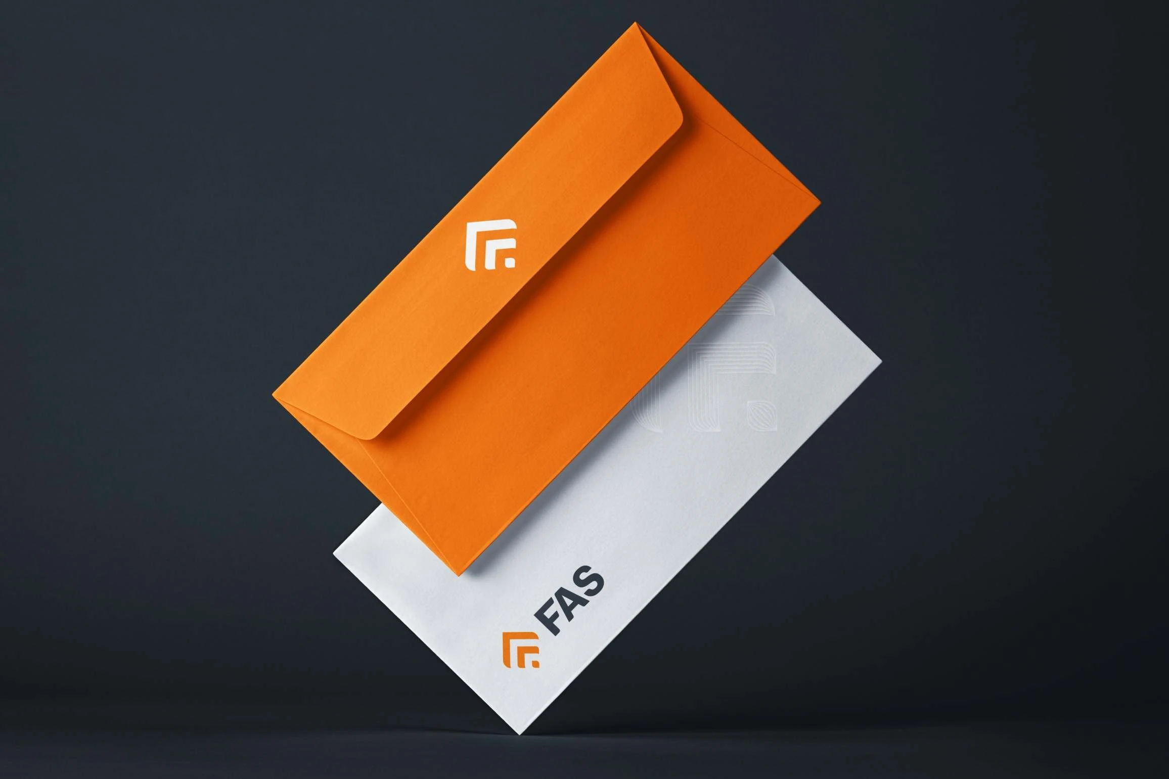 Two envelopes floating on dark slate: an orange one with the mark in white, and a white one with the FAS logo and a faint embossed line mark.