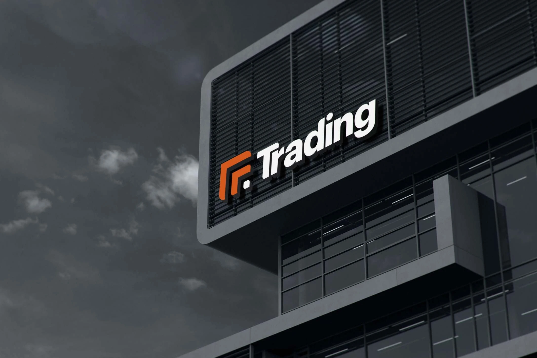 The Trading logo in white letters with the orange mark, mounted high on a dark building with louvred panels, under a grey, cloudy sky.