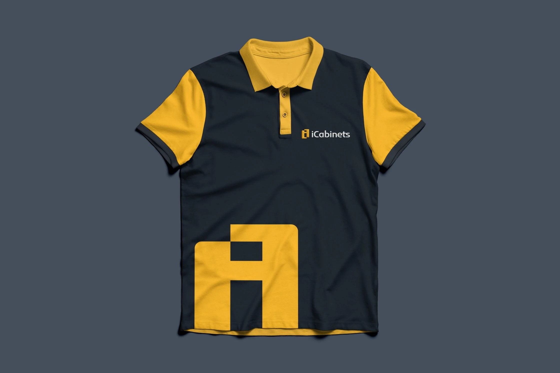 A black polo shirt with yellow collar and sleeves, the iCabinets logo on the chest and a large yellow emblem cropped at the hem, on slate grey.