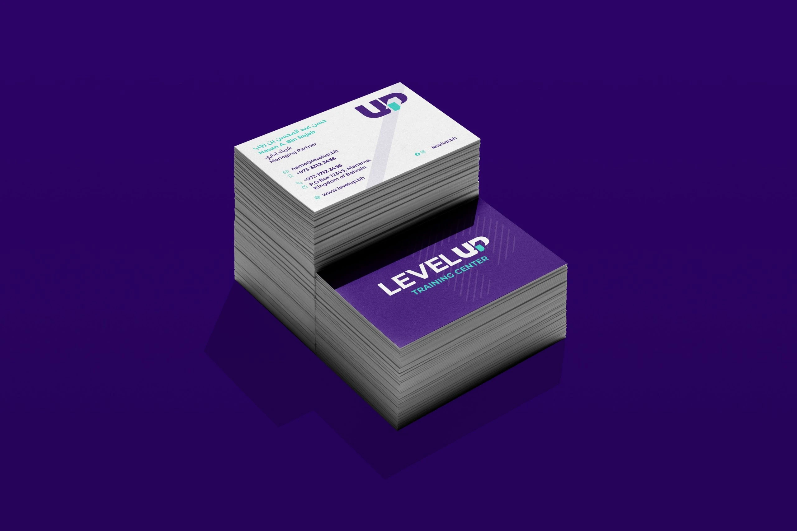 Two stacks of Level Up business cards on purple: white backs with the UP monogram and contact details, and purple fronts with the logo.
