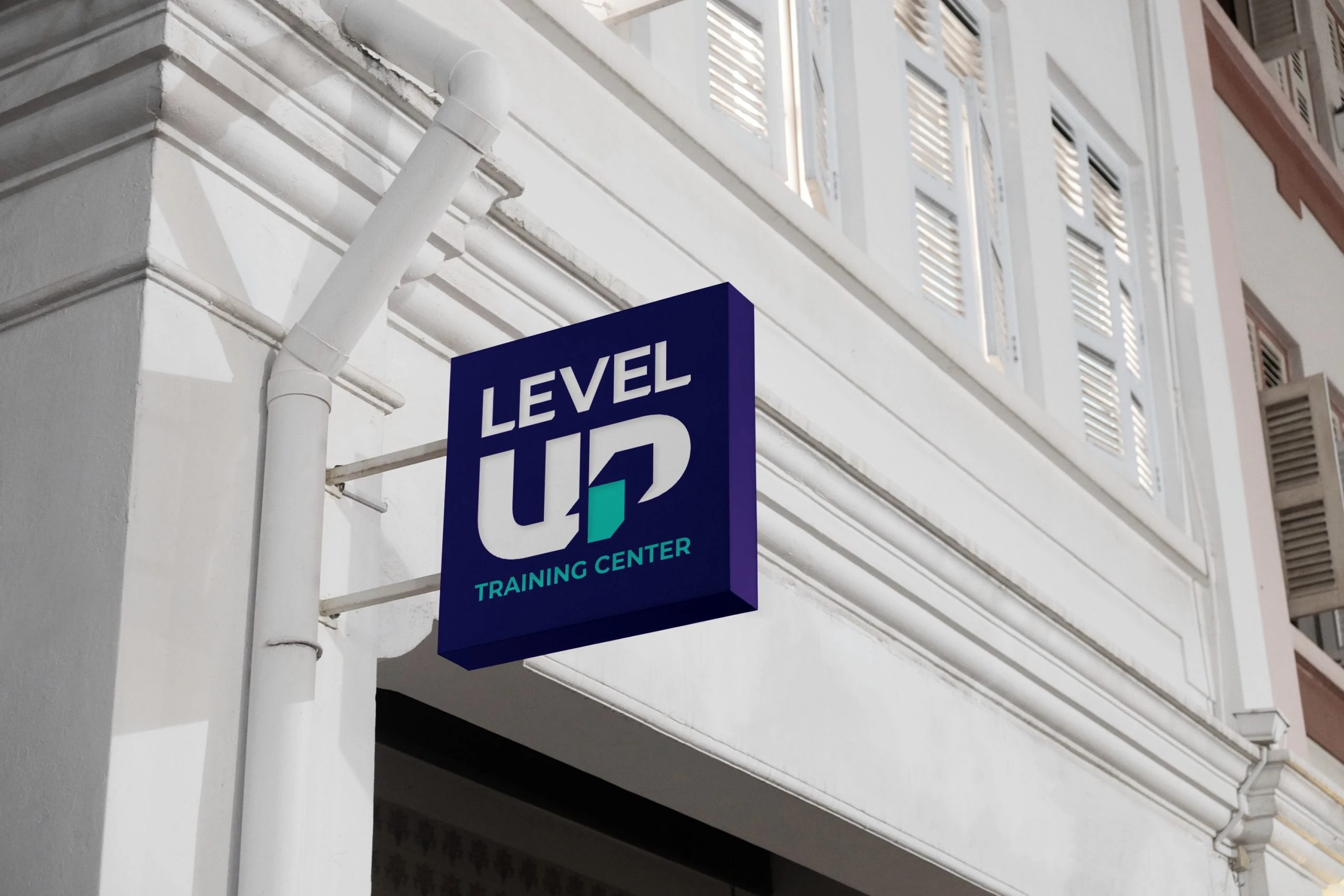 A square purple sign projecting from a white building, with the stacked logo: LEVEL over UP in white, the P’s stem and TRAINING CENTER in turquoise.