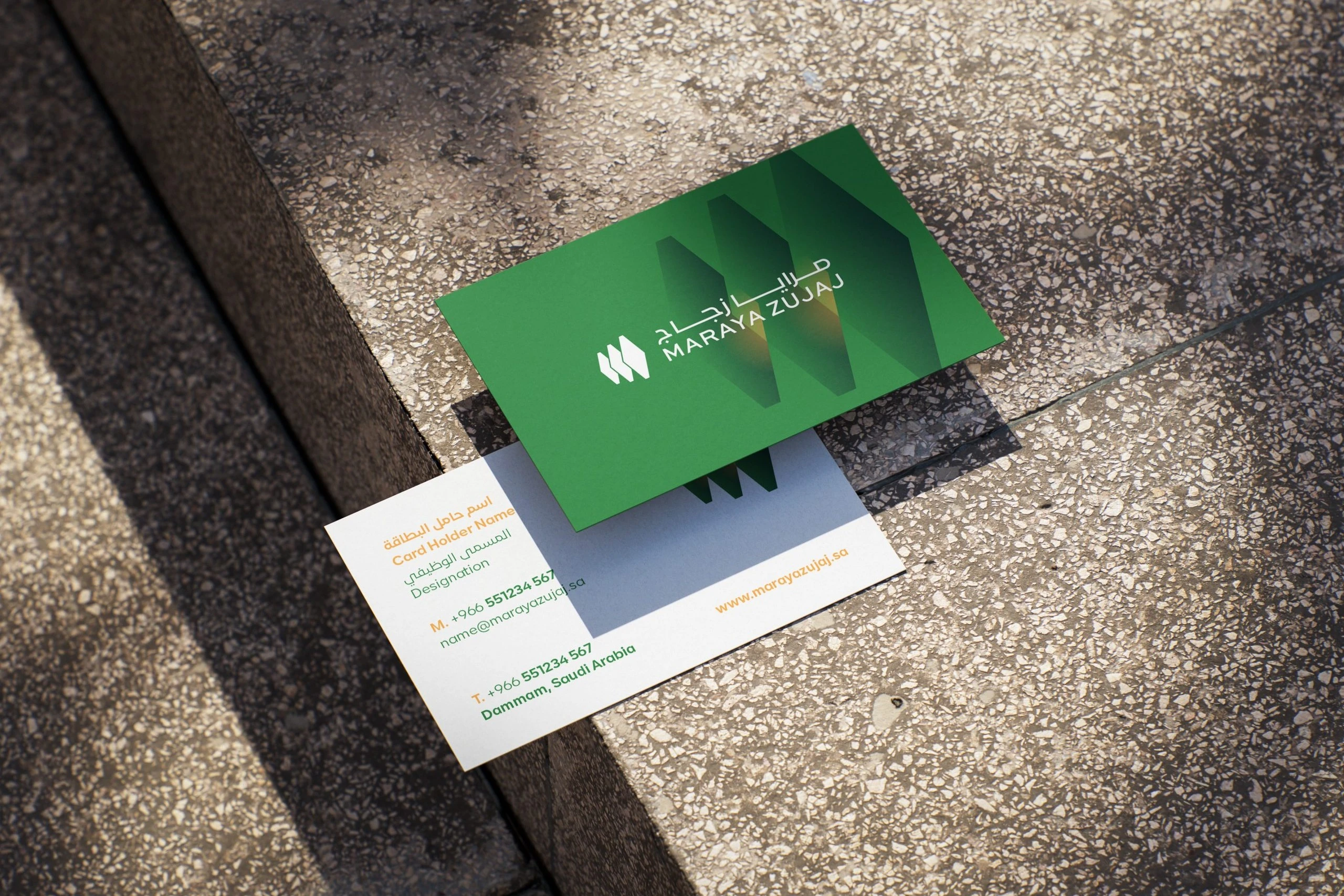 Maraya Zujaj business cards on speckled stone steps: a green front with the white logo and large hexagons, over a white back with placeholder contact details.