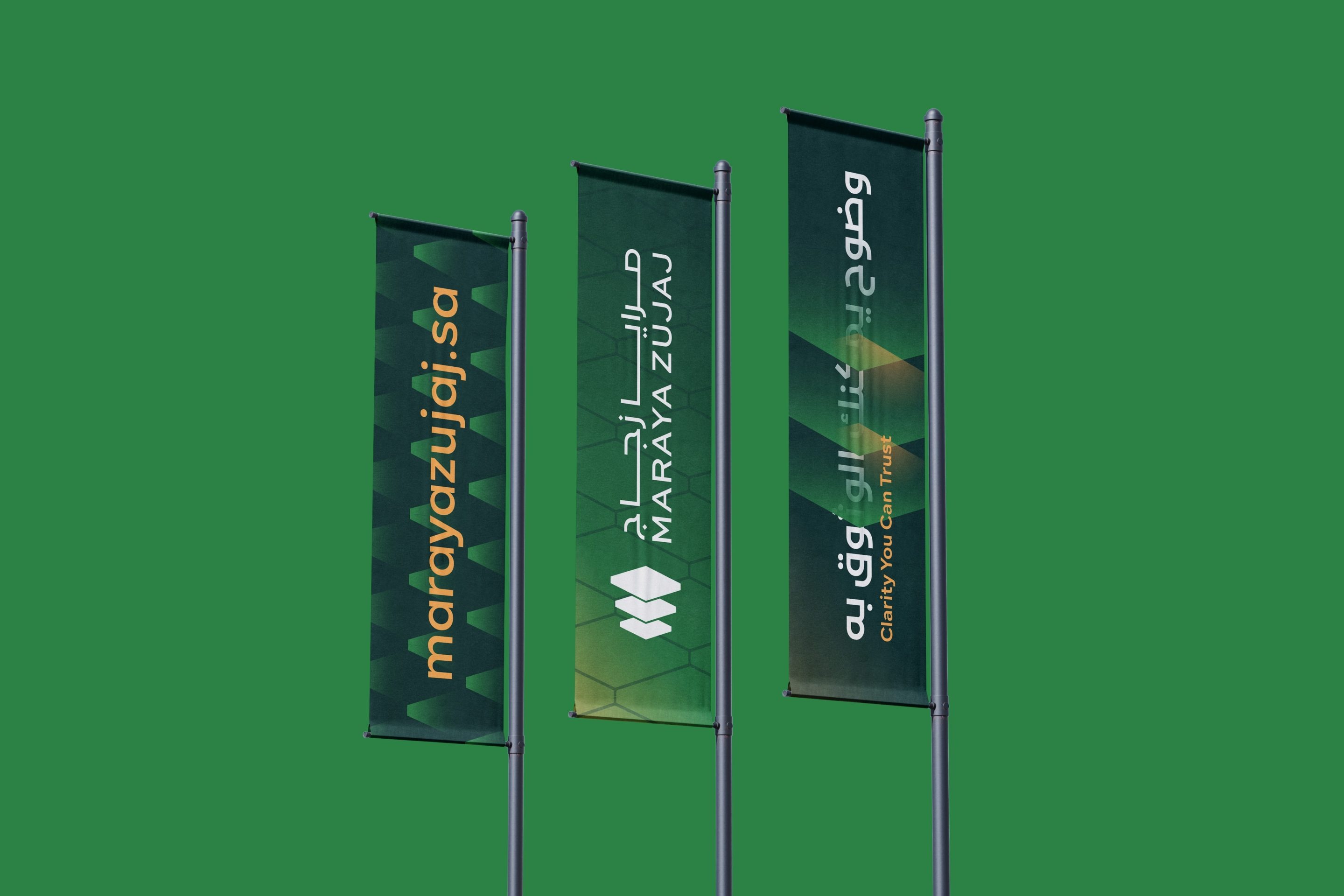 Three pole banners on green: marayazujaj.sa in orange over the hexagon pattern, the logo in white, and وضوح يمكنك الوثوق به with Clarity You Can Trust.