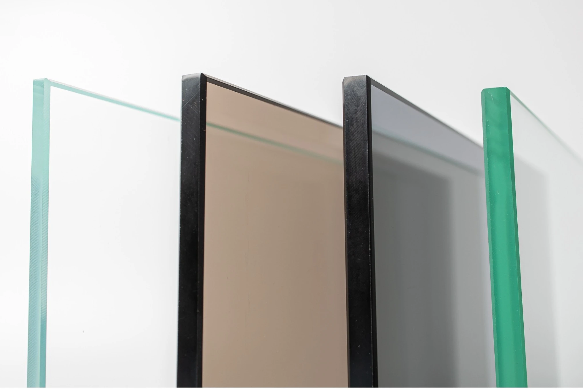 Inspiration board: four panes of glass seen edge-on against white, one clear, one bronze and one grey with black edges, and one green.