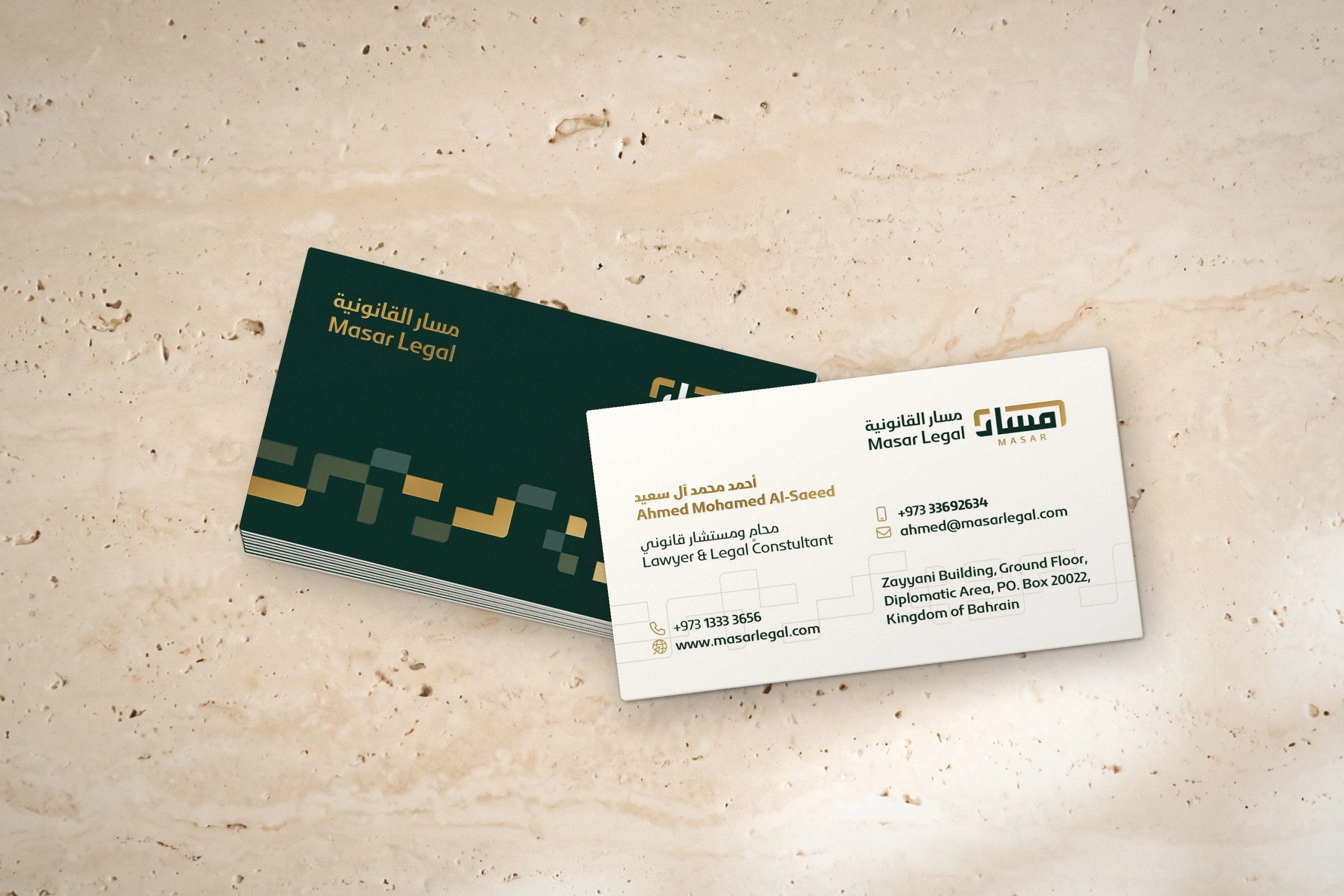 Masar business cards on travertine: a stack of green backs with the gold pattern, and a white front with the logo and contact details.