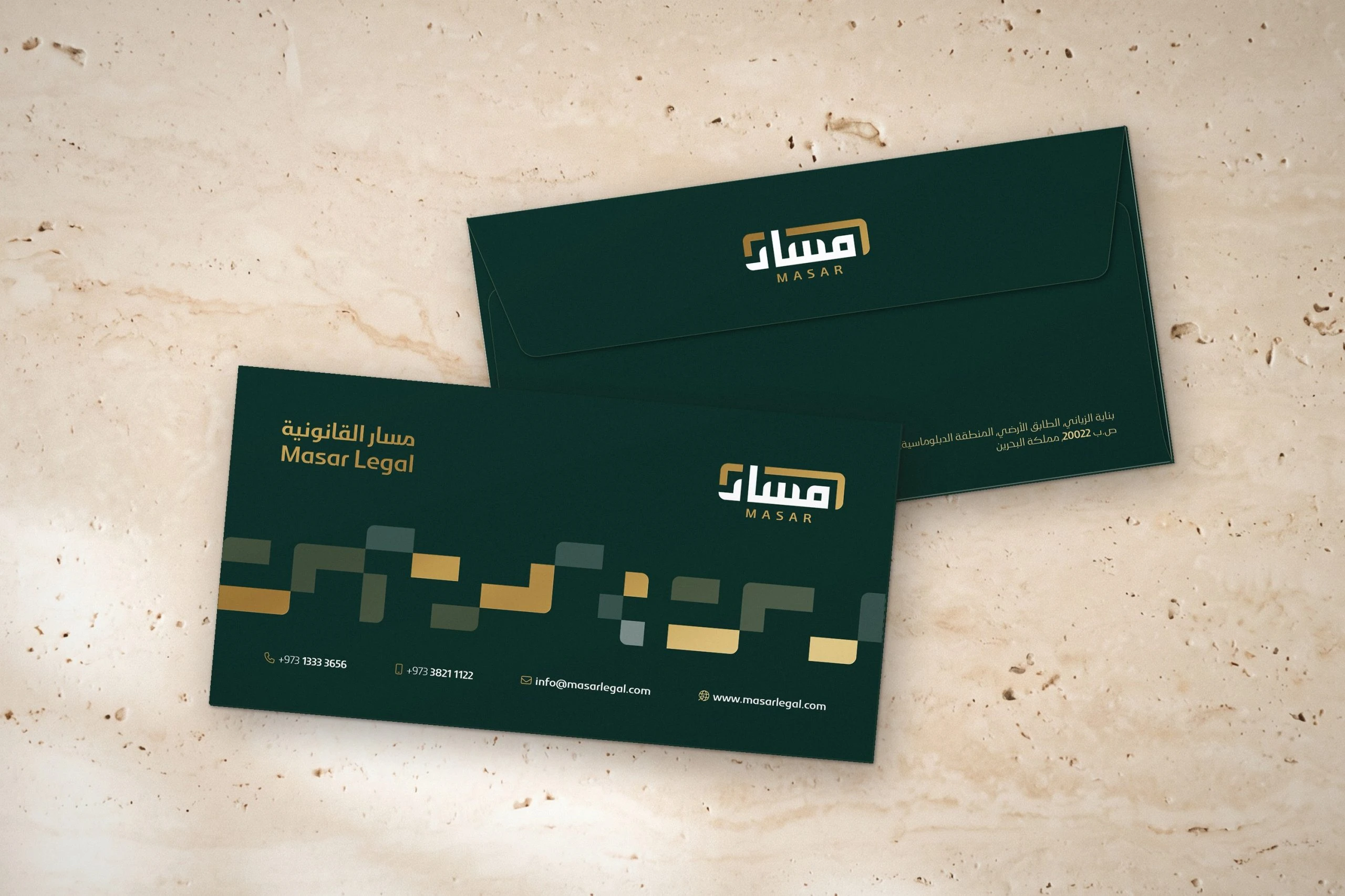 Two DL envelopes on travertine: the front with the logotype, logo, pattern and contacts, and the back with the logo on the flap and the address.