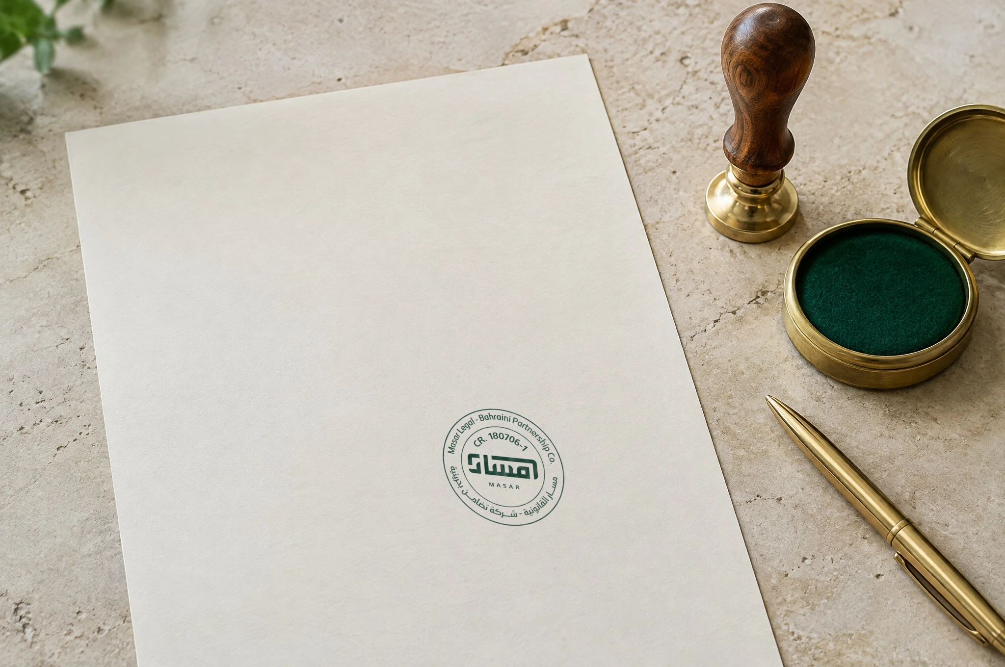 The round Masar company stamp in green ink on cream paper, beside a wooden stamp and a brass ink pad.