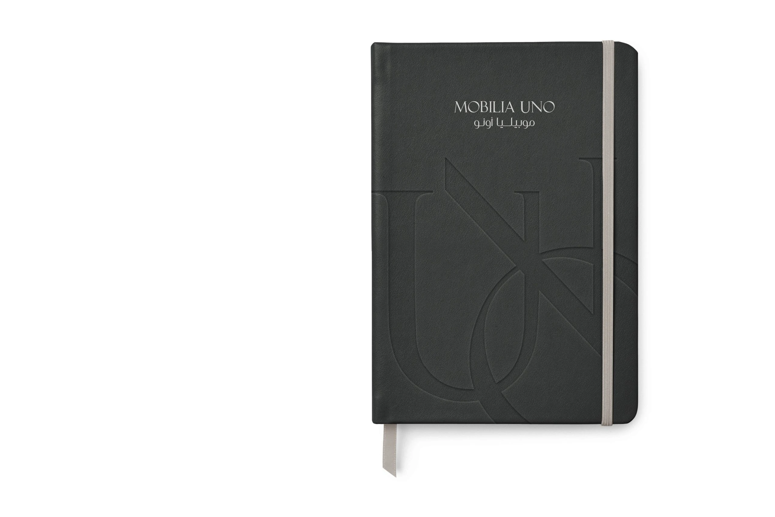 A black notebook with an elastic band, the logo at the top and the monogram debossed on its cover.