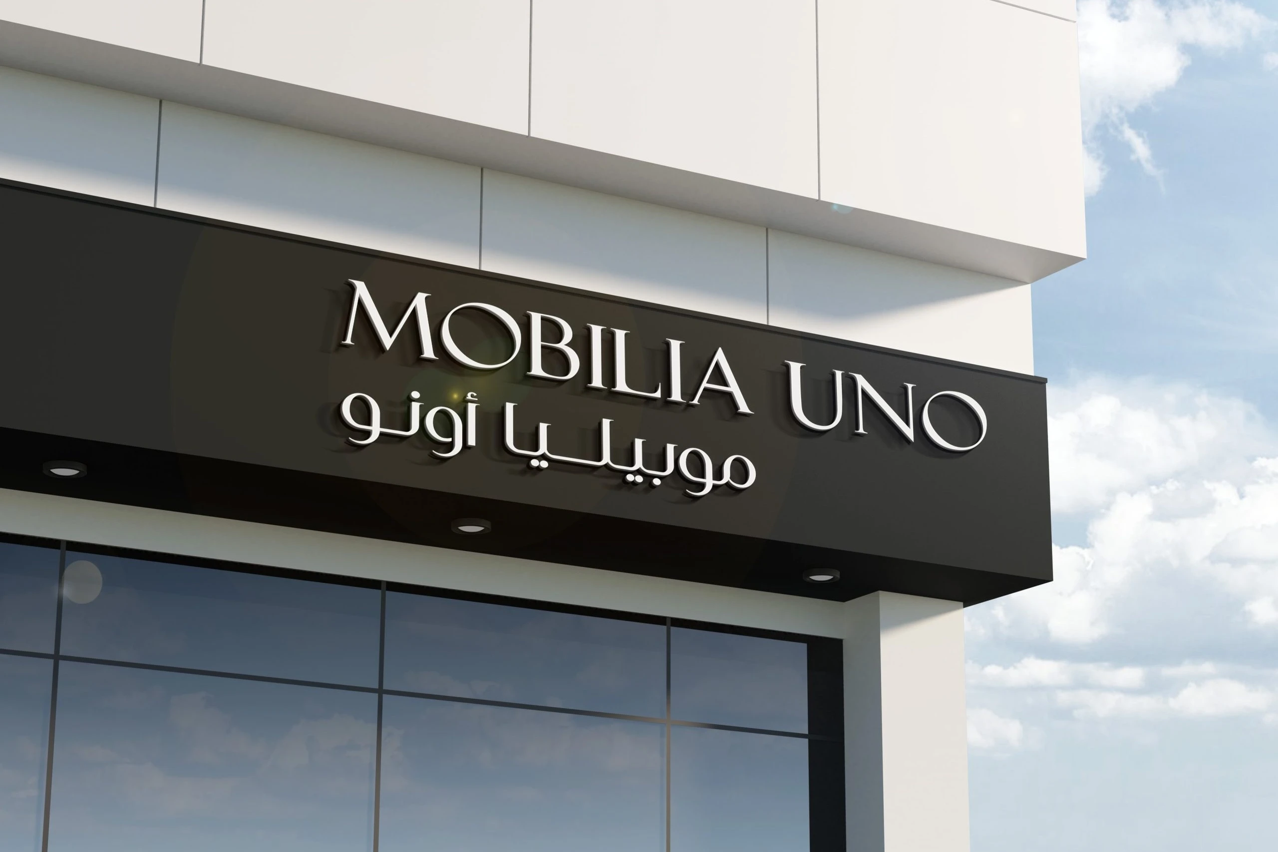 The shop sign: MOBILIA UNO and موبيليا أونو in lit white letters on a black fascia above a glass front, against a blue sky.