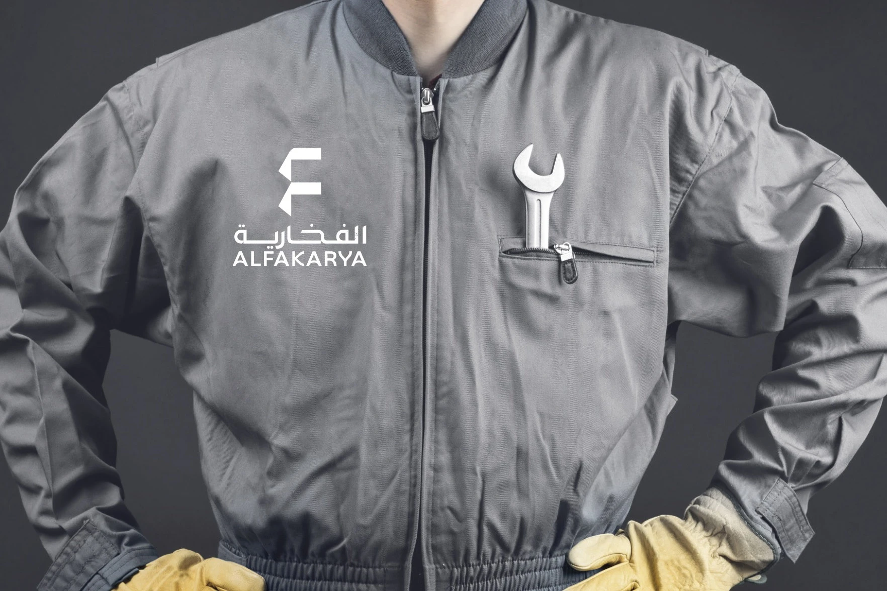 A grey work jacket with the Alfakarya logo in white on the chest and a wrench in the pocket.