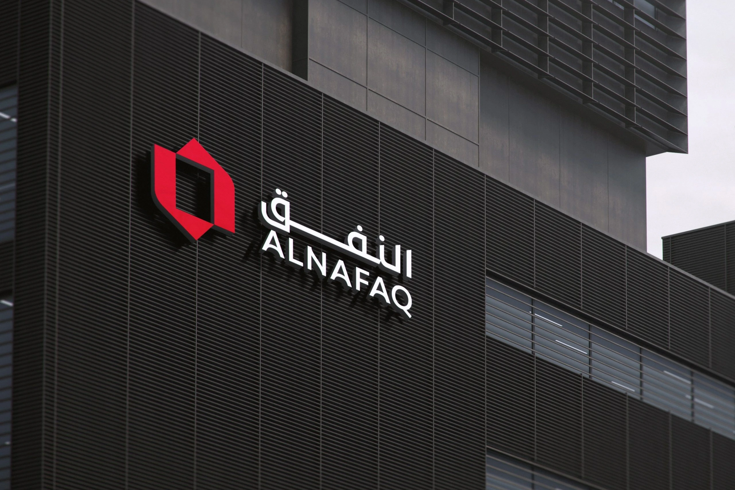 The Alnafaq logo in raised letters, the red frame and white names, on a dark modern building.