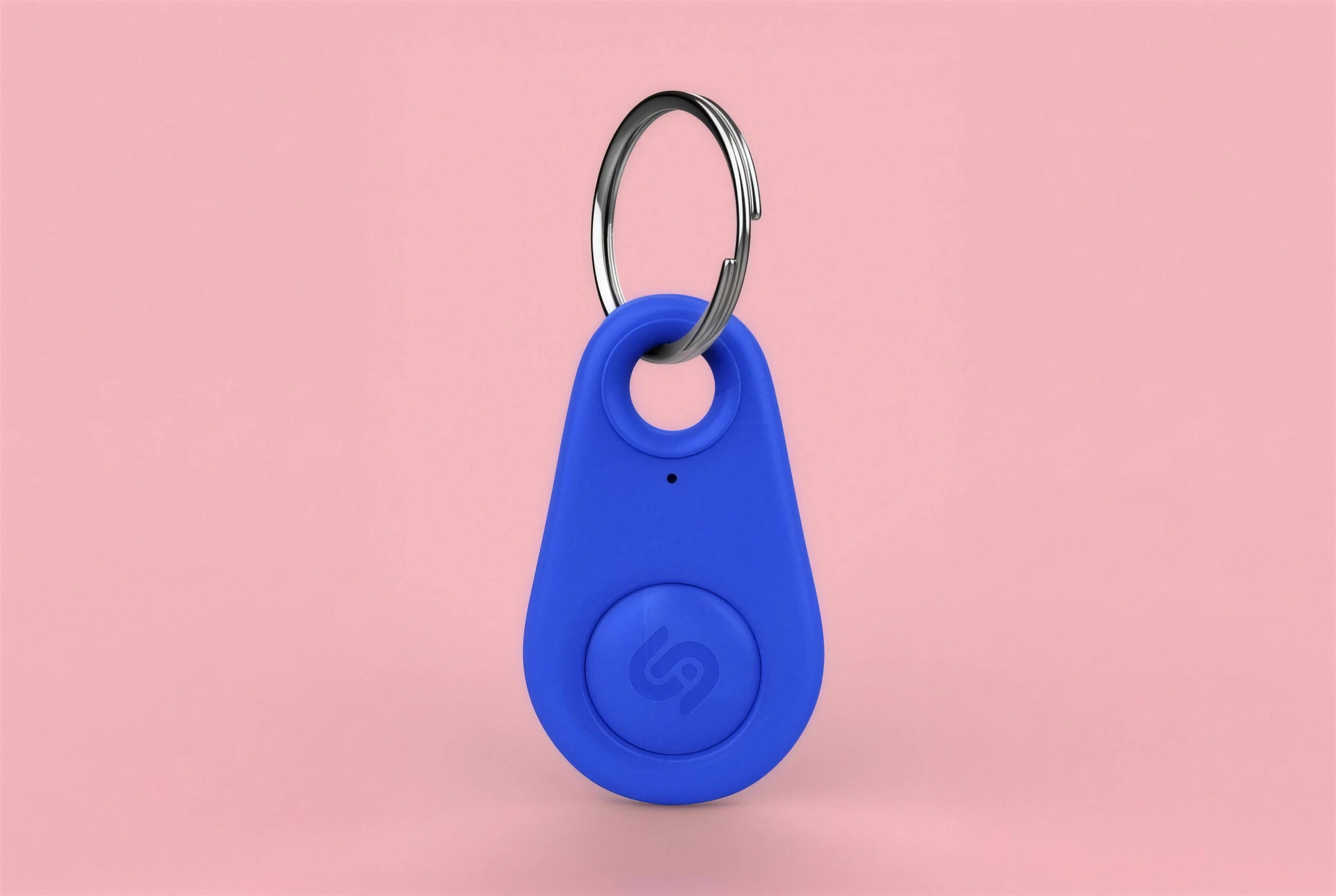 A blue teardrop-shaped key tracker with the monogram, on pink.