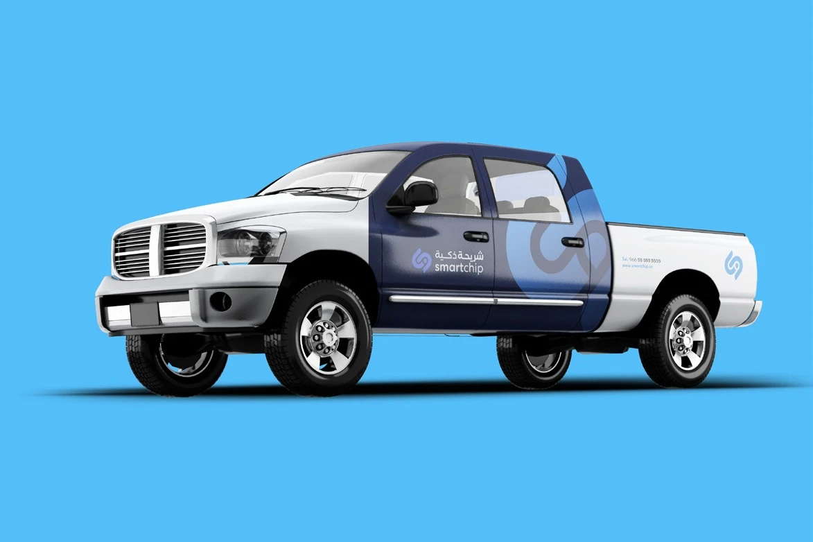 A white pickup truck wrapped with the dark blue monogram and the Smart Chip logo, on light blue.