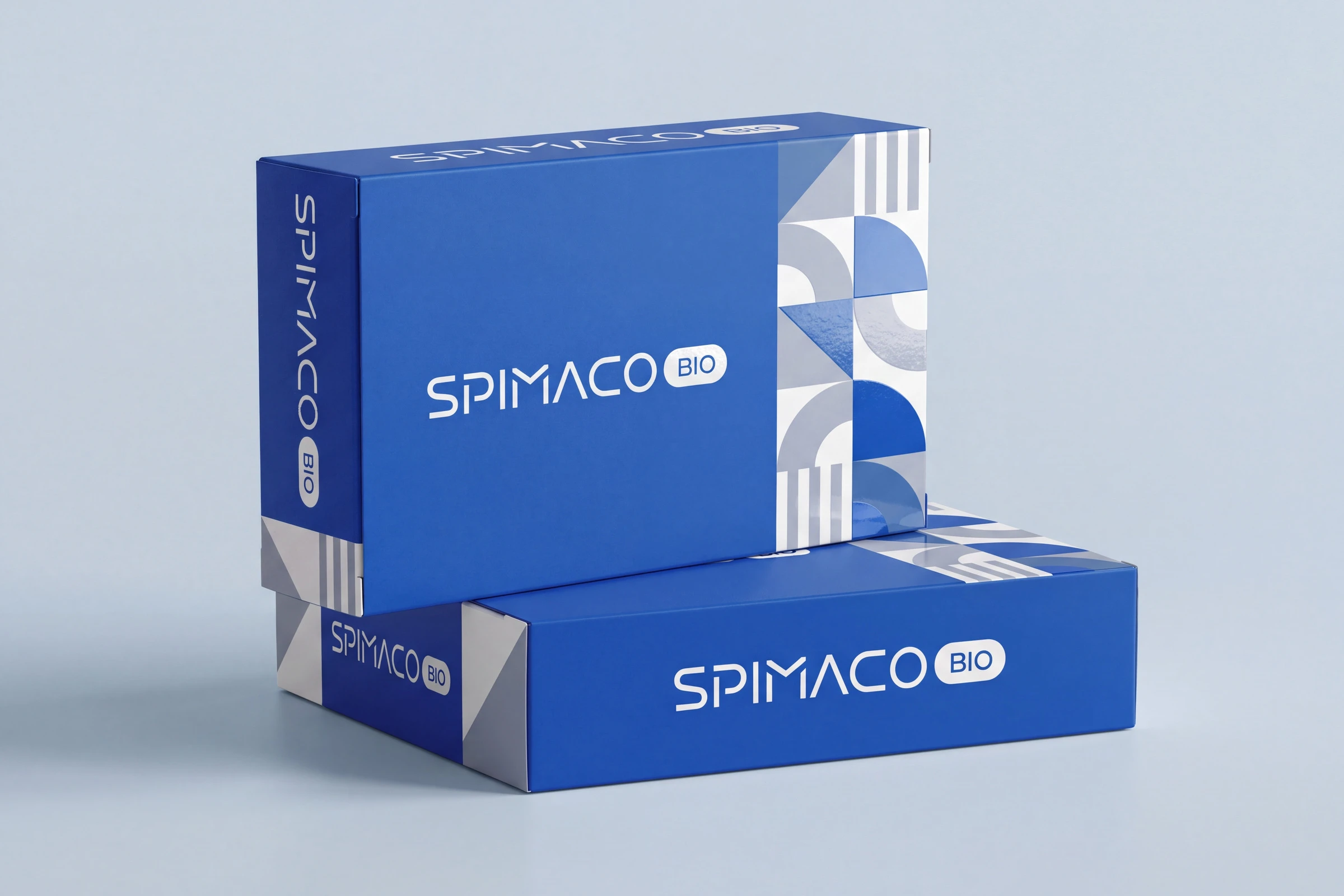 Two blue SPIMACO BIO cartons, one standing on the other, with the wordmark in white and the pattern of quarter circles, triangles and stripes down one end.