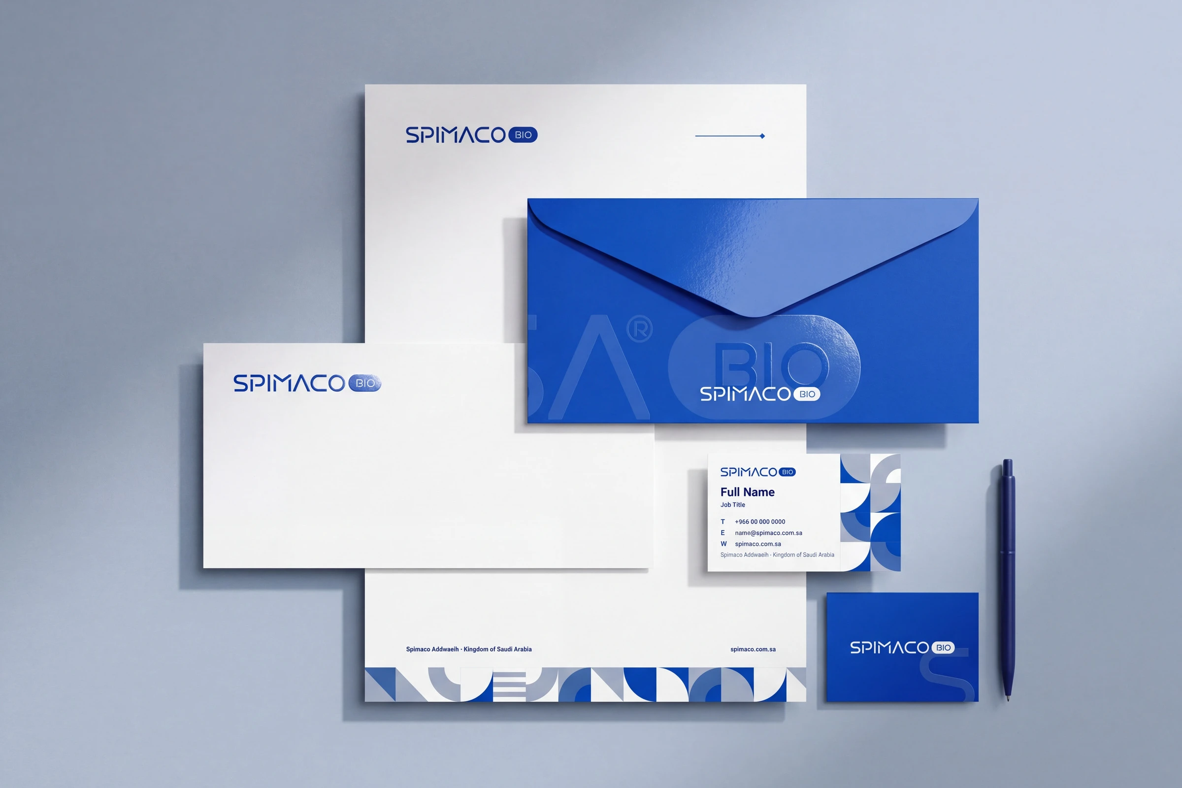 A letterhead, two envelopes, a white and a blue business card and a blue pen: the wordmark in blue on white and white on blue, the monogram large on the blue envelope, and the pattern along the foot of the letterhead.