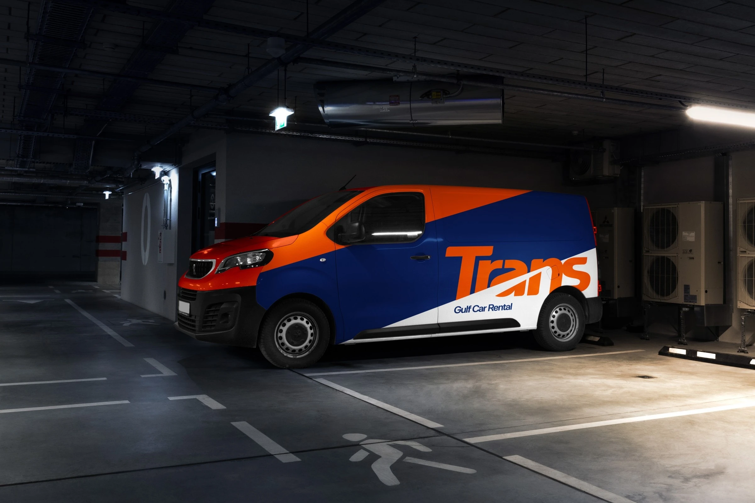 A van wrapped in orange, navy and white diagonals with the Trans logotype and Gulf Car Rental on its side, parked in an underground car park.