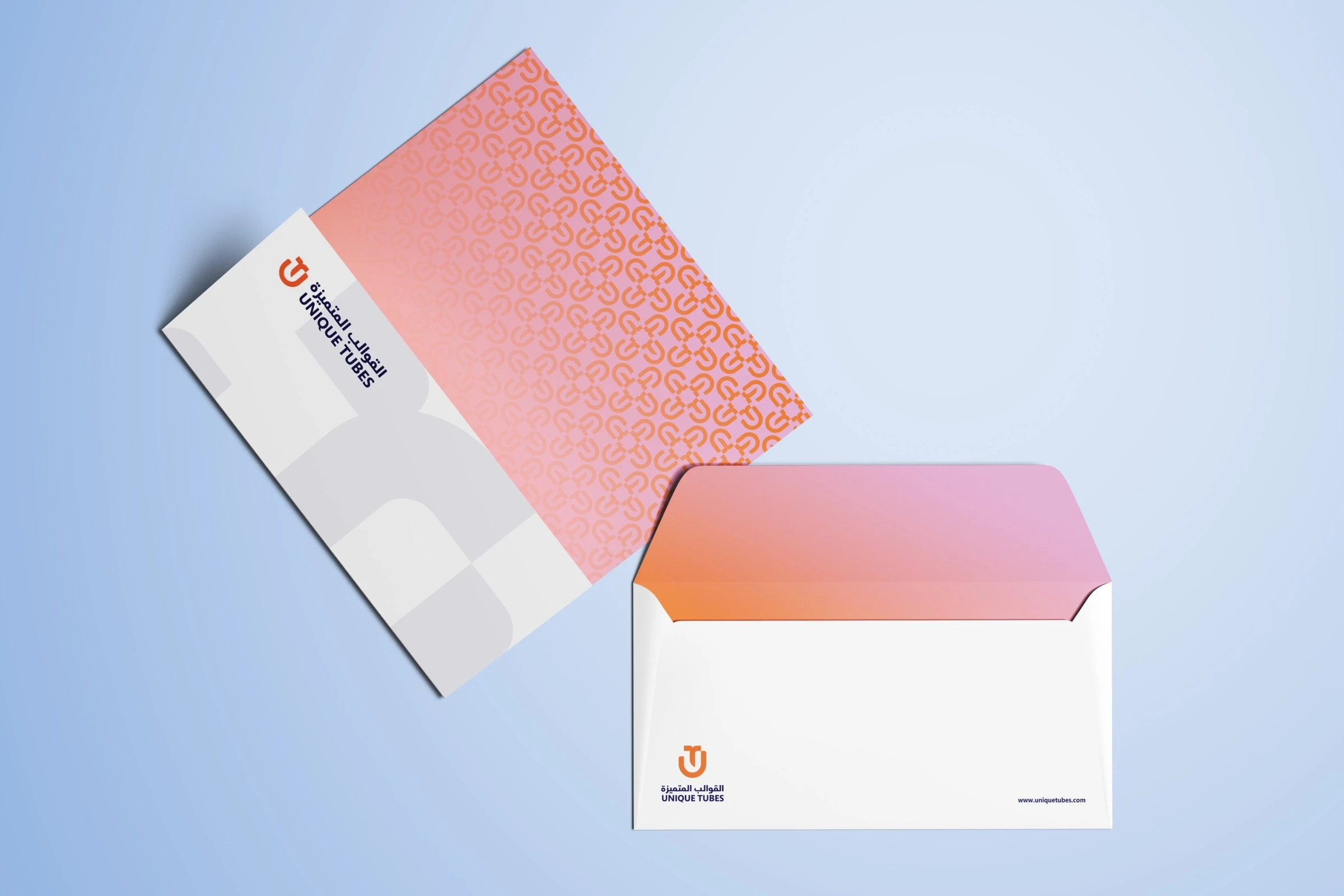 A sheet with the logo, a grey cropped monogram and the orange monogram pattern on a pink gradient, beside an open white envelope lined in the same gradient, on pale blue.