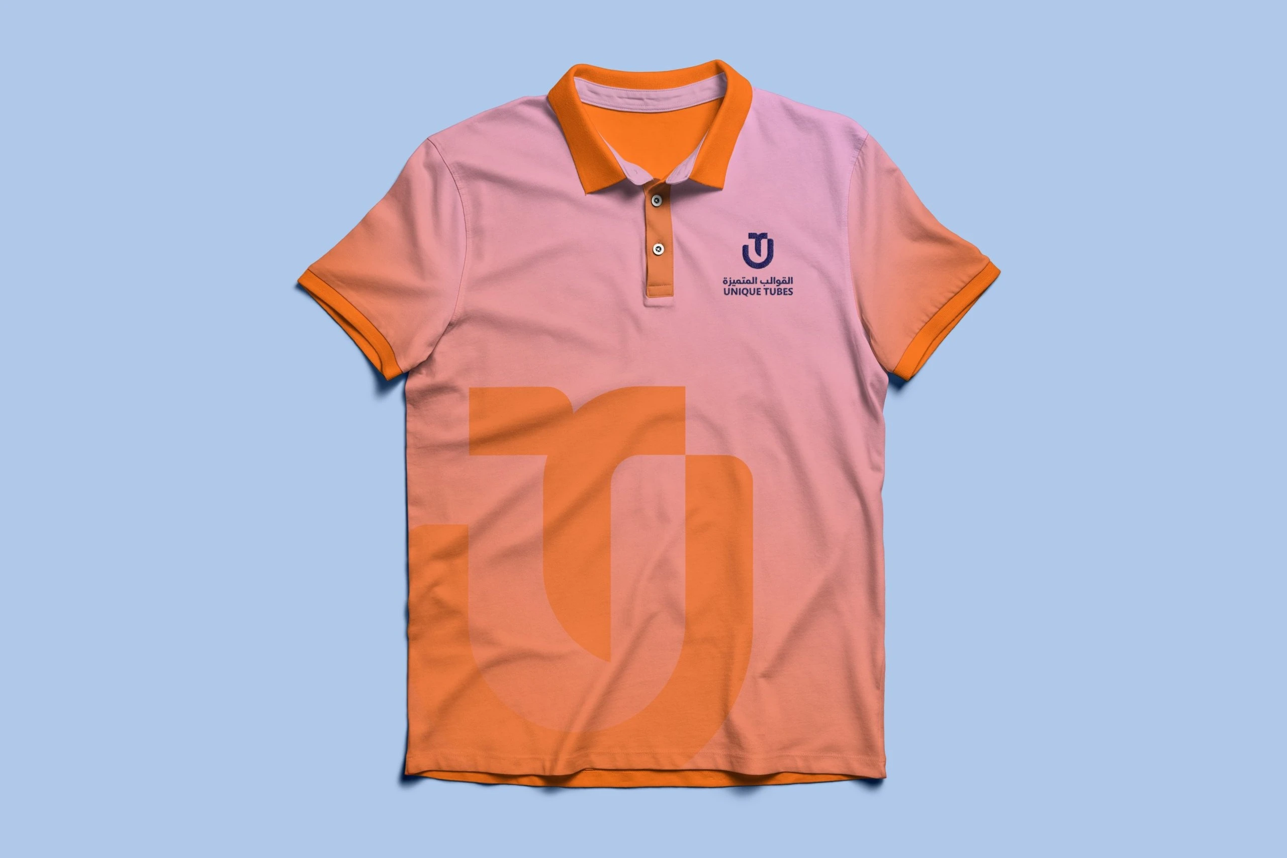 A polo shirt fading from pink to orange, with orange collar and cuffs, the dark blue logo on the chest and a large orange monogram across the front, on pale blue.