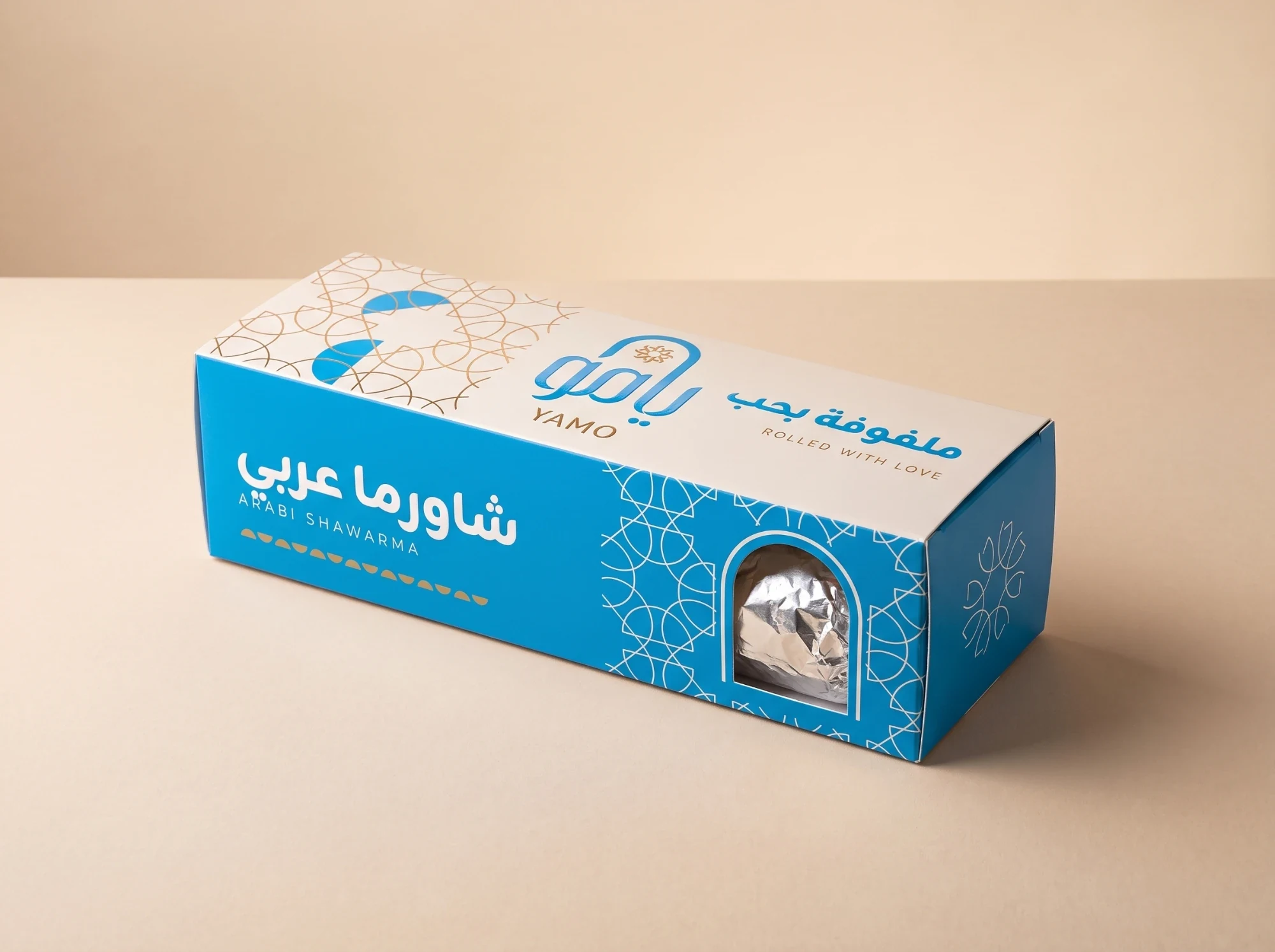 A long blue and cream box, شاورما عربي, ARABI SHAWARMA, with the logo, ملفوفة بحب, ROLLED WITH LOVE, and an arched window onto a foil-wrapped roll.